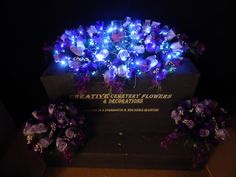 the headstone is adorned with purple flowers and blue led lights, which are on display