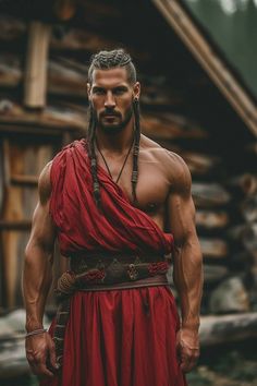 a man with long hair and braids wearing a red dress standing in front of a log cabin