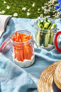 carrots, cucumbers and other vegetables are in jars on a blue blanket