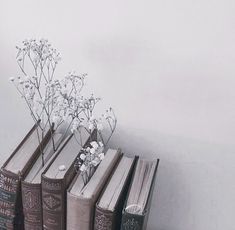 three books are stacked on top of each other with flowers in them