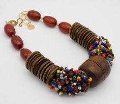 Heads are going to turn! Bold...dramatic....entrance making necklace!  Taking center-stage is a vintage handcarved African wooden spindle whorl...flanked by my handmade brass discs and a plethora of tiny African trade beads hand coiled on wire.  Large, handcarved coconut shell discs, more of my handmade brass discs and handmade Moroccan beads separated by little brass rectangles complete this tribal-style necklace.  Necklace fastens with my signature, large fancy brass clasp and matte 18KT over brass, soldered link chain. Chain is high quality and is tarnish resistant.  Length adjusts from about  19 - 21 inches. My handstampd maker's mark tag hangs from chain. Traditional Brown Beaded Chain, Africa Vintage, Spindle Whorls, African Beads Necklace, African Necklace, Beading Jewelery, African Trade Beads, Ethnic Necklaces, Beads Bracelet Design