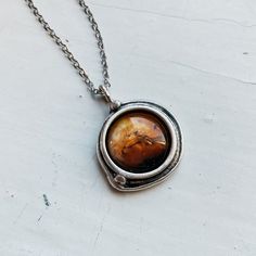 There has been a lot of buzz about the past, current, and future projects surrounding the exploration of our planetary neighbor. We wanted to celebrate! This unique handcrafted silver tone pendant features the beloved red planet in our Solar System: Mars! There are two "orbiting" silver beads around the planet that represent the rocky Martian moons, Deimos and Phobos. A unique statement for any lover of the cosmos!Pendant Size: 7/8" (23mm)Chain Length: 18" (46cm)Materials: Silver plated brass, g Galaxy Jewelry, Planet Necklace, Science Jewelry, Red Planet, Moon Pendant Necklace, Our Solar System, The Martian, Moon Pendant, Solar System