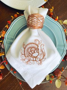 an embroidered napkin sits on top of a plate next to a white dish cloth and twine