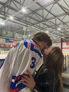 a man and woman kissing each other in front of an ice hockey jersey on display