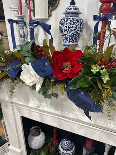 a fireplace mantel decorated with blue and white vases, greenery and poinsettis