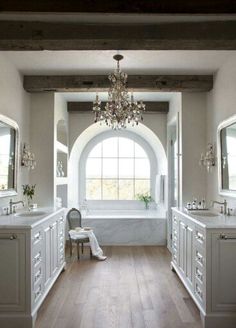 a large bathroom with two sinks, tub and chandelier in the middle of it