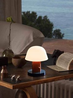 a lamp sitting on top of a wooden table next to a book and other items