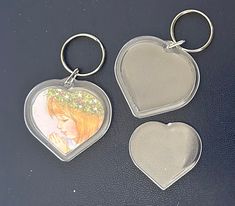 three heart shaped keychains with pictures on them sitting next to each other in front of a black surface