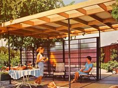 a woman and two children sitting at a table under a pergolated covered patio