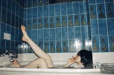 a woman laying in a bathtub with her legs up