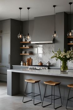 a kitchen with gray walls and wooden stools in front of the island countertop