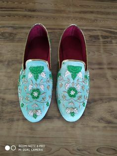 a pair of shoes that are on top of a wooden floor and one has flowers painted on it