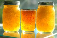 three jars filled with yellow liquid sitting on top of a table