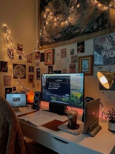 a desk with a computer, laptop and other items on it in front of a decorated wall