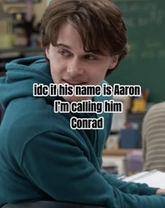 a young man sitting at a desk in front of a blackboard with the caption idic, his name is aaron i'm calling him concord