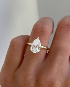 a woman's hand with a diamond ring on top of her finger, showing the center stone