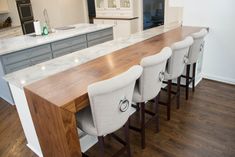 a kitchen island with four stools next to it and an oven in the background