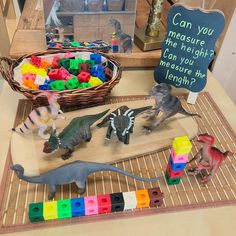 toy dinosaurs and other toys on a table with a sign that says can you measure the height?