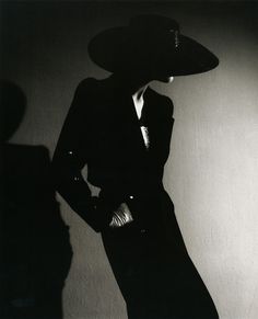 a black and white photo of a woman in a hat with her hands on her hips