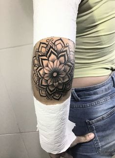 a woman with a black and white tattoo on her arm holding a roll of toilet paper