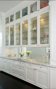 a kitchen with white cabinets and marble counter tops