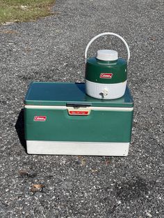 a green and white cooler sitting on top of gravel