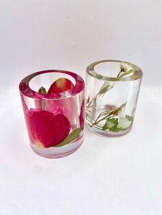 two glass vases with flowers and leaves on them