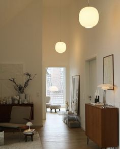 a living room filled with lots of furniture and lights hanging from the ceiling next to a doorway