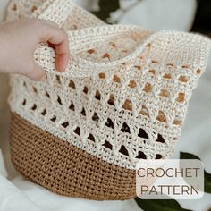 a hand holding onto a crocheted purse on top of a white bed sheet