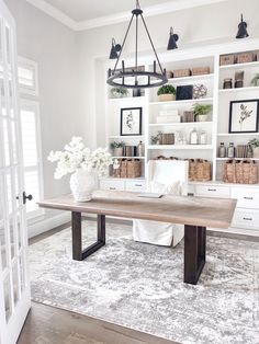 a dining room table with white flowers in vases on the top and shelves behind it