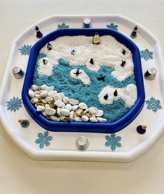 a blue and white tray filled with sand and sea shells in the shape of polar bears