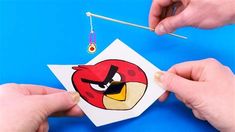 someone is cutting out an angry bird paper craft with scissors and thread on a blue background