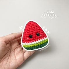 a hand holding a crocheted watermelon sticker