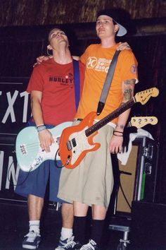 two men standing next to each other with guitars