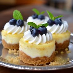 three desserts on a silver plate with blueberries and whipped cream in the center