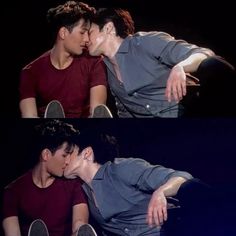 two young men kissing each other while sitting on the floor in front of a black background