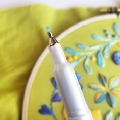 a white pen sitting on top of a green plate next to a yellow cloth covered tablecloth