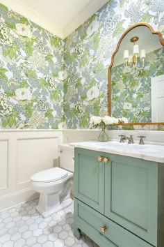 a bathroom with floral wallpaper and green cabinetry is featured in this instagram