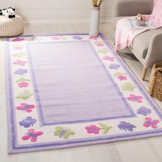 a white rug with purple and pink flowers on it in front of a gray chair