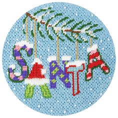 a cross stitch christmas ornament hanging from a tree branch with stockings and stockings on it