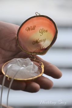 a hand holding an ornament with the words, will you marry me?