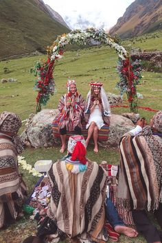 some people are sitting in the grass with blankets on their heads and one is wearing a headdress