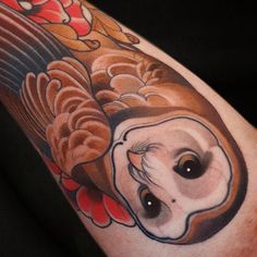 an owl tattoo on the arm with red and orange flowers around its eyes, in front of a black background