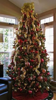 a decorated christmas tree with red, gold and white ornaments in a living room area