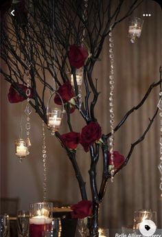 a vase filled with roses and candles sitting on top of a table next to a tree