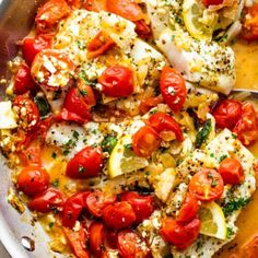 a pan filled with fish covered in tomatoes and lemons, garnished with parmesan cheese