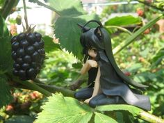 a figurine sitting on top of a tree branch next to some blackberries