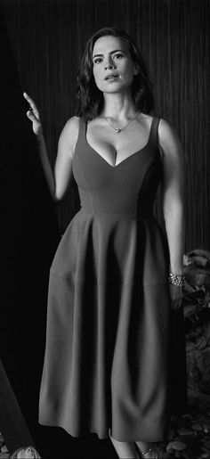 a woman in a short dress posing for a black and white photo with her hand on her hip