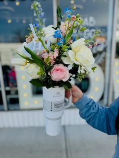 a woman is holding a vase with flowers in it on the side of the road