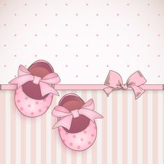 two pink baby shoes with bows hanging from the side on a striped wallpaper background